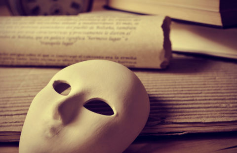 playwriting and performing arts a pile of books and a mask, depicting the concept of playwriting and performing arts